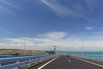 Fototapeta na wymiar Cars go on the Crimean bridge across the Kerch Strait. On the left is the construction of the railway bridge