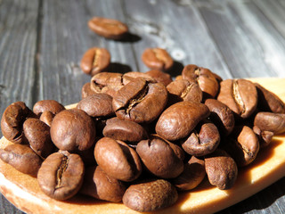 Spoon with coffee beans on a wooden table