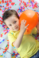 Fototapeta na wymiar niño feliz jugando con un globo en un suelo lleno de confetti