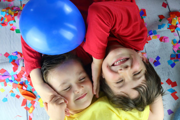 niños tumbados sobre confetti riendo en una fiesta de cumpleaños