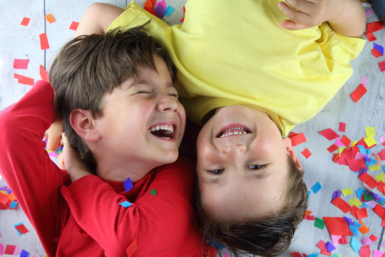 ni&ntilde;os tumbados sobre confetti riendo en una fiesta de cumplea&ntilde;os