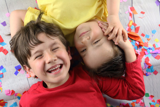 ni&ntilde;os tumbados sobre confetti riendo en una fiesta de cumplea&ntilde;os
