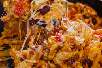 Pan with roasted vegetables, chicken and melted cheese for burritos close-up of cooking burrito food