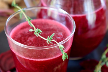 Beetroot beverage in a glass decorated with thyme. Close-up 