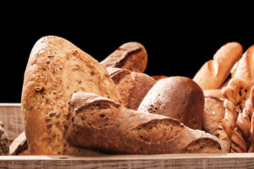 Fragrant bread on the table. Food concept in a wooden box on black background
