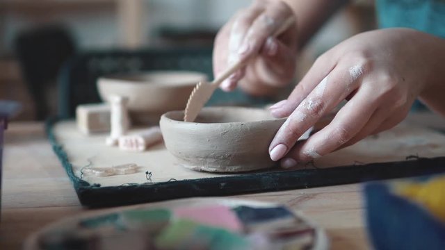 girl is busy with creative work. the process of creating a dish of clay. female hands closeup. patterning on raw clay