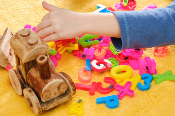 Obraz na płótnie Canvas Little baby hand playing with colorful toys and letters