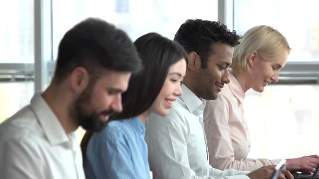 Row of smiling workers in office. Programmers in office, windows bright background, selective camera focus.