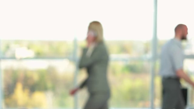 Busy people in skyscraper office walking. Blurred office workers walking and handshaking, side view, blured background for keying.