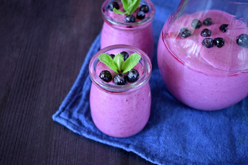 Blueberry smoothie in glass jars topped with berries and mint 