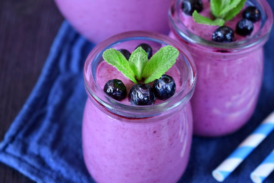 Blueberry smoothie in glass jars topped with berries and mint 