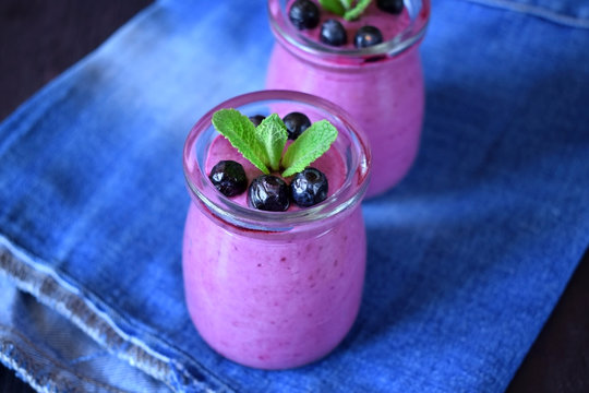 Blueberry smoothie in glass jars topped with berries and mint 