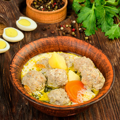 Tasty homemade soup with meatballs and eggs and vegetables on a wooden rustic table. Square.