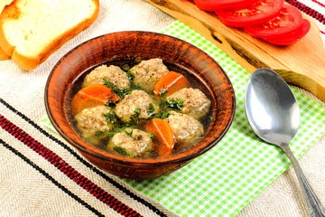 Tasty homemade diet soup with meatballs and vegetables on paper napkin.