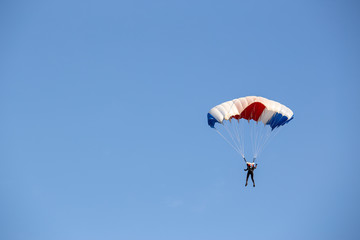 isolated skydiver  control colorful parachute gliding after free fall jump with blue sky background