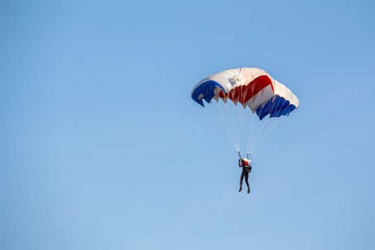 isolated skydiver  control colorful parachute gliding after free fall jump with blue sky background