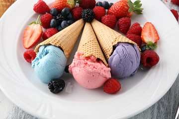 Set of ice cream scoops of different colors and flavours with blueberries, raspberries and blackberries.
