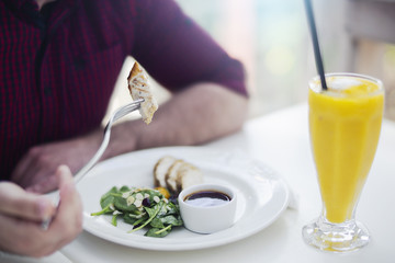 Young attractive man drinking smoothie and eating salad at lunch time.