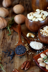 Different nuts and seeds in wooden spoons and bowls
