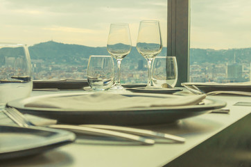 glasses and cutlery on the restaurant table with a view of the city