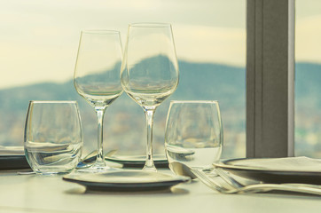 glasses and cutlery on the restaurant table with a view of the city