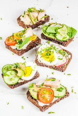 Set of various danish open sandwiches Smorrebrod with fish, egg and fresh vegetables, white marble background copy space