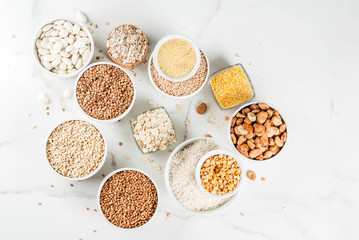 Selection various types cereal grains groats  in different bowl on white marble background, copy...