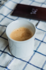 Fresh Coffee and black phone on white napkin background