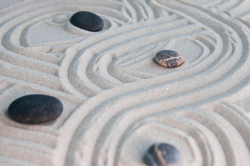 Fototapeta na wymiar Pyramids of gray zen stones on light sand. Concept of harmony, balance and meditation, spa, massage, relax