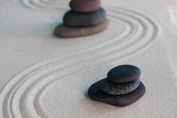 Fototapeta na wymiar Pyramids of gray zen stones on light sand. Concept of harmony, balance and meditation, spa, massage, relax
