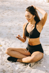 Fototapeta na wymiar Young pretty smiling fashion tanned sporty style women dressed in black bikini sitting on a beach 