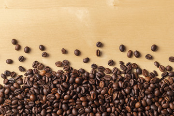 Spilled fresh coffee beans on blonde wooden table