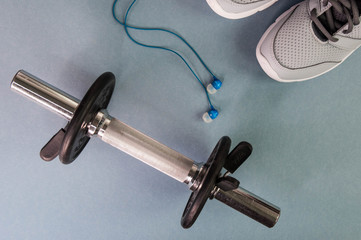 Gray sneakers, dumbbell and blue headphones. Sport and fitness concept.