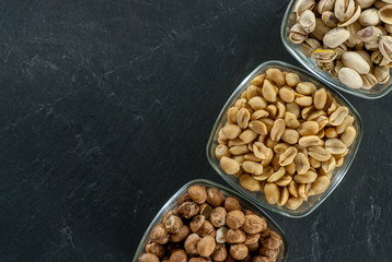 bowls with assorted nuts like hazelnuts pistachio and peanuts on black slate with copy space healthy life concept