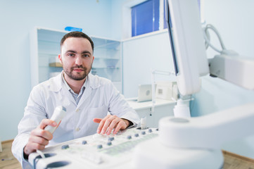 Young male doctor explaining ultrasound scan to pregnant woman in hospital