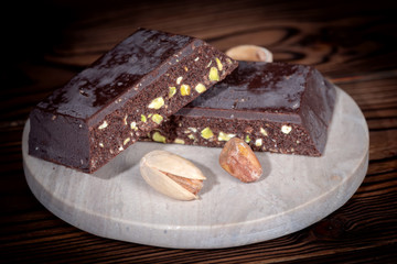 portion of dark chocolate with nut of pistachios on wooden table