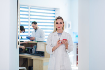 Obraz premium Portrait of happy female surgeon reading message at mobile phone