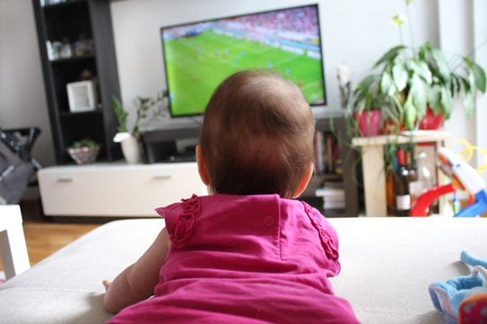 baby girl watching a soccer on TV