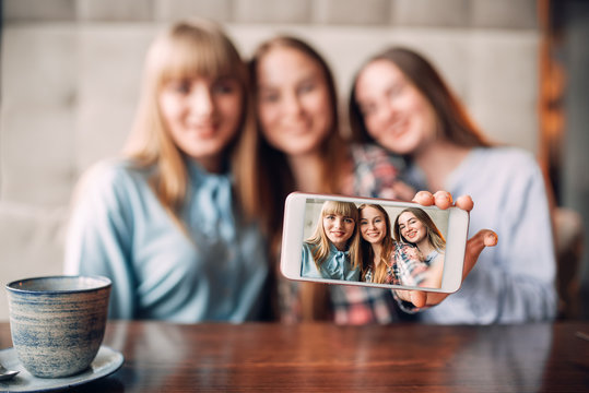 Three girlfriends makes selfie on camera in cafe
