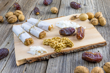 Dates bar wrapped in paper with walnuts and coconut on a wooden board