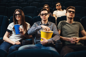 Obraz premium People with popcorn watching movie in cinema