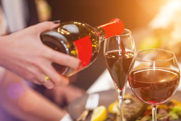 Waiter pouring luxury wine into the wineglass in the restaurant. concept of perfect wedding party service