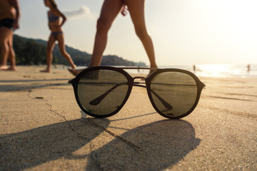 sunglasses on the sandy beach in front of water and sunny sky with clouds