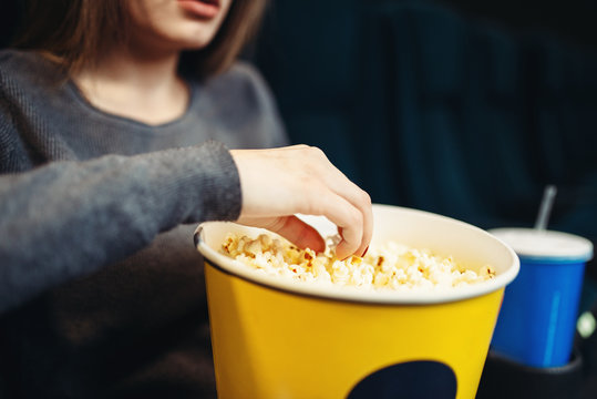 Woman eats popcorn while watching movie in cinema
