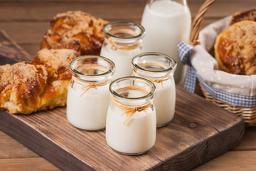 Jars with milk and bread buns on a cutting board 