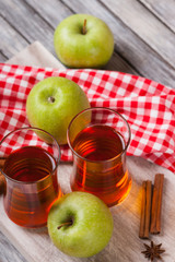 Apple juice in glasses, spices and apples on wooden cutting table 