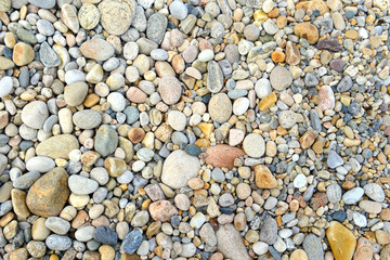Closeup of rocks, pebbles and boulders on rocky beach which have been eroded smooth by the wave action of the water
