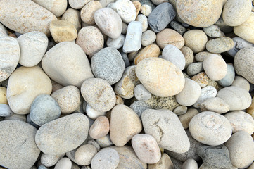 Closeup of rocks, pebbles and boulders on rocky beach which have been eroded smooth by the wave action of the water