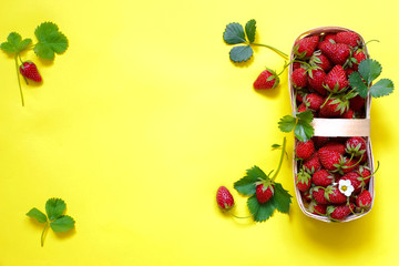 basket with fresh strawberries on a yellow background top view