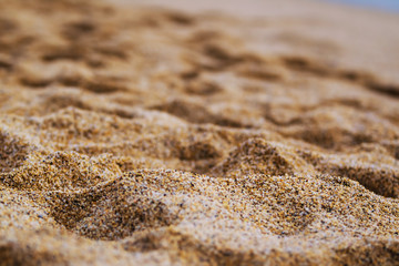 Fototapeta na wymiar close up photo of the orange grainy sand rippled by the wind with footprints left by the visitors of the beach